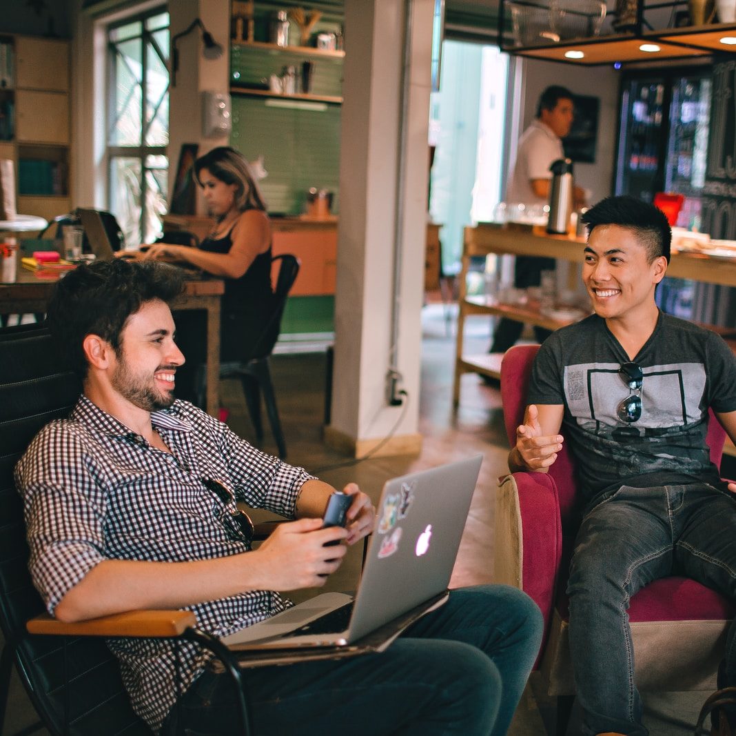 two men laughing white sitting on chairs